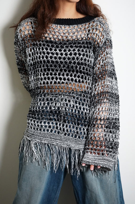 Person wearing a patterned sweater and jeans against a plain background